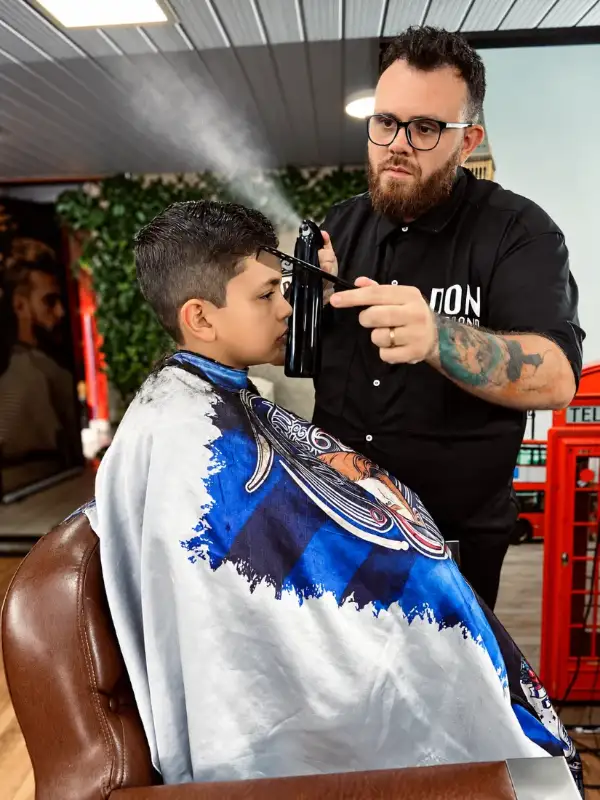 Barbeiro atendendo criança, com cabine telefônica vermelha ao fundo